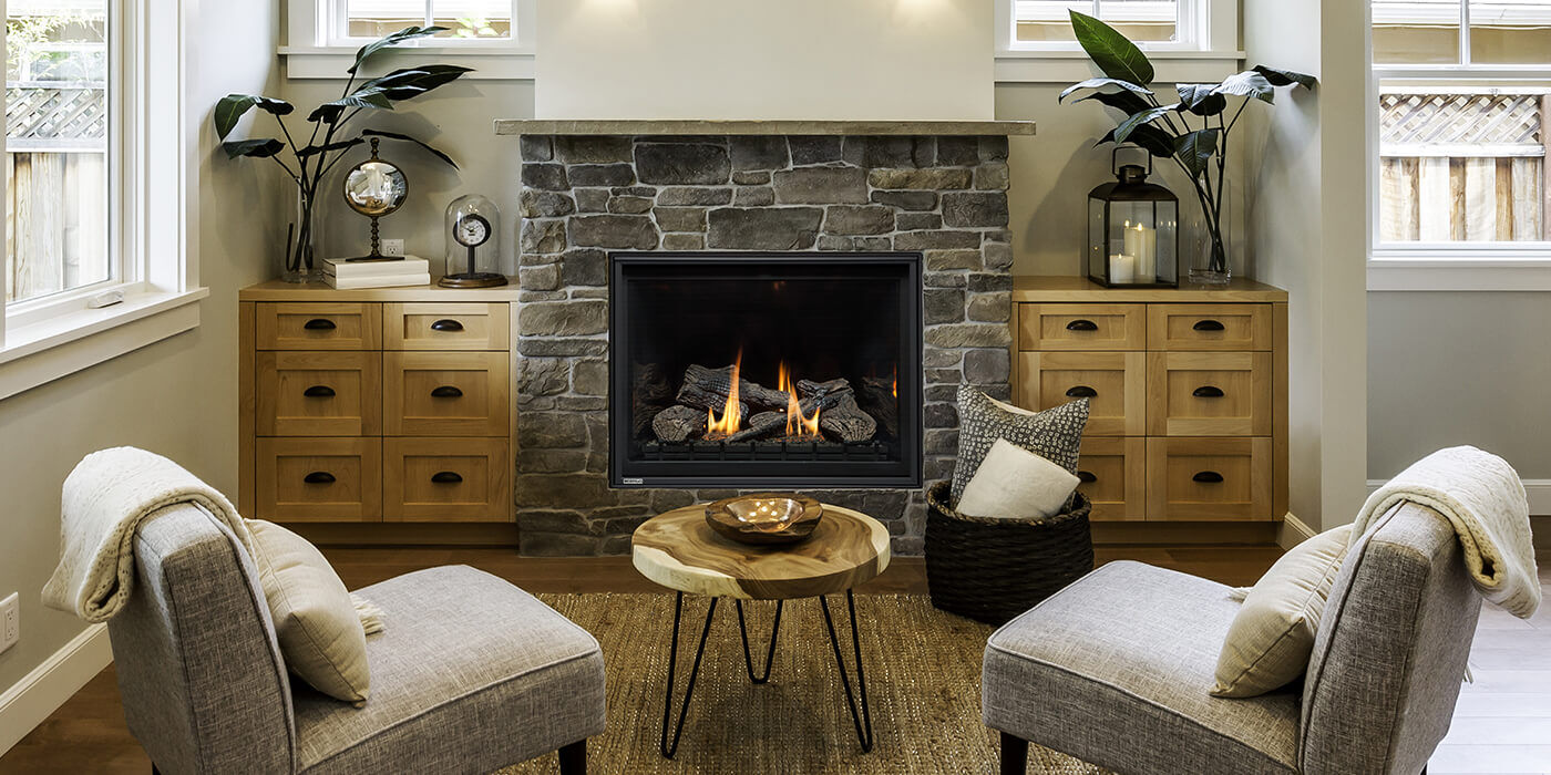 A cozy rustic sitting area with a square gas fireplace, natural stone surround, and custom cabinets next to the hearth.