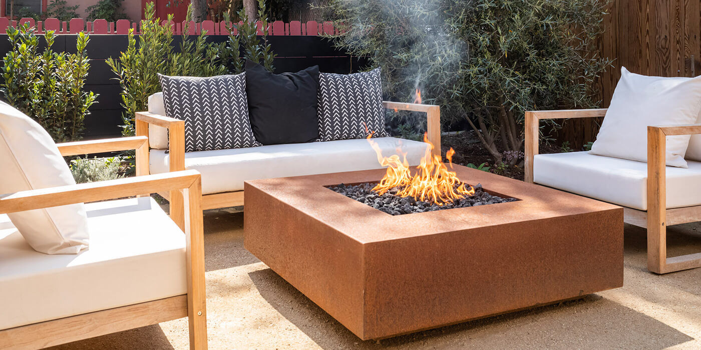 A large, square-shaped Corten Steel gas fire pit 