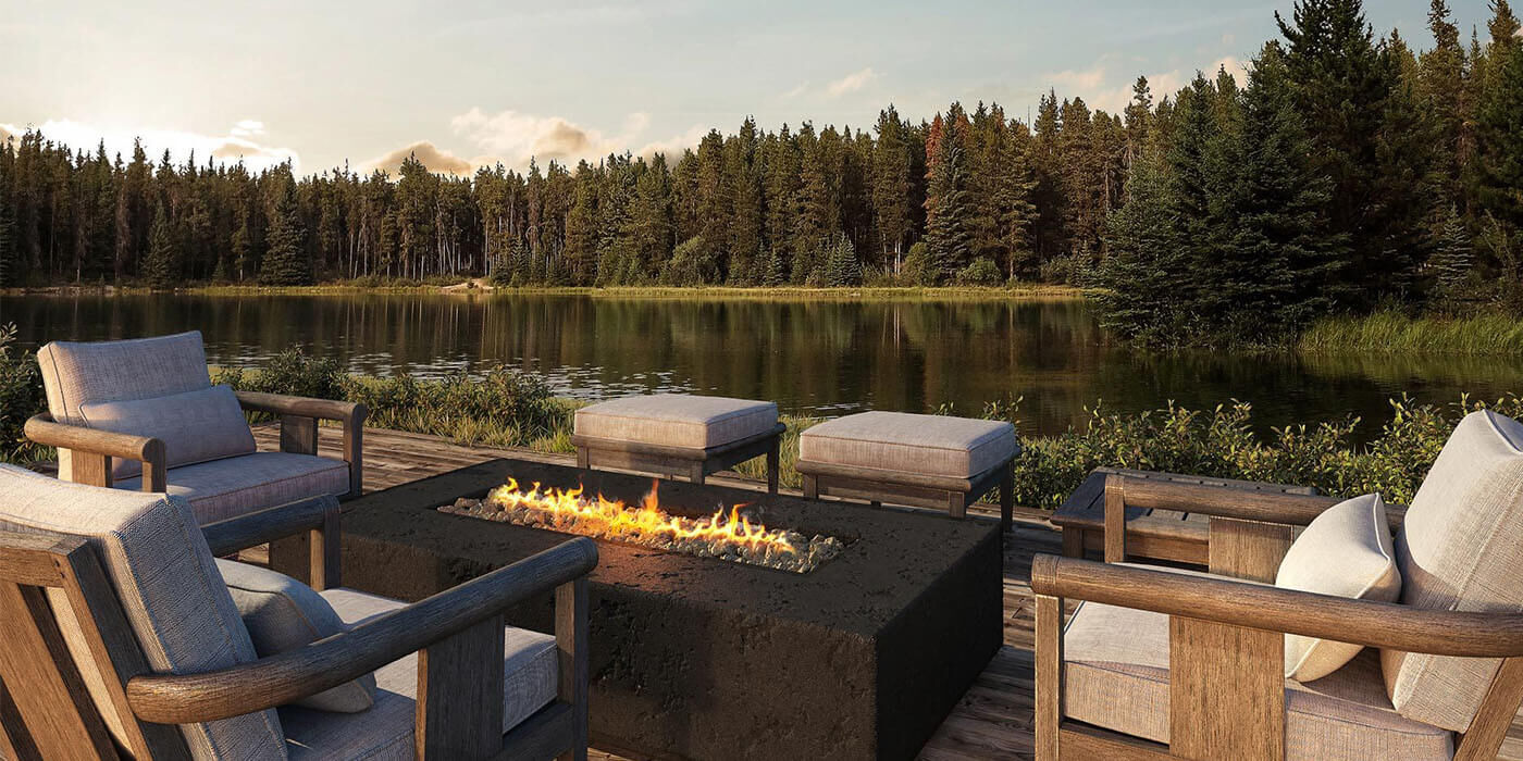 A linear gas fire pit installed on an outdoor deck overlooking a lake