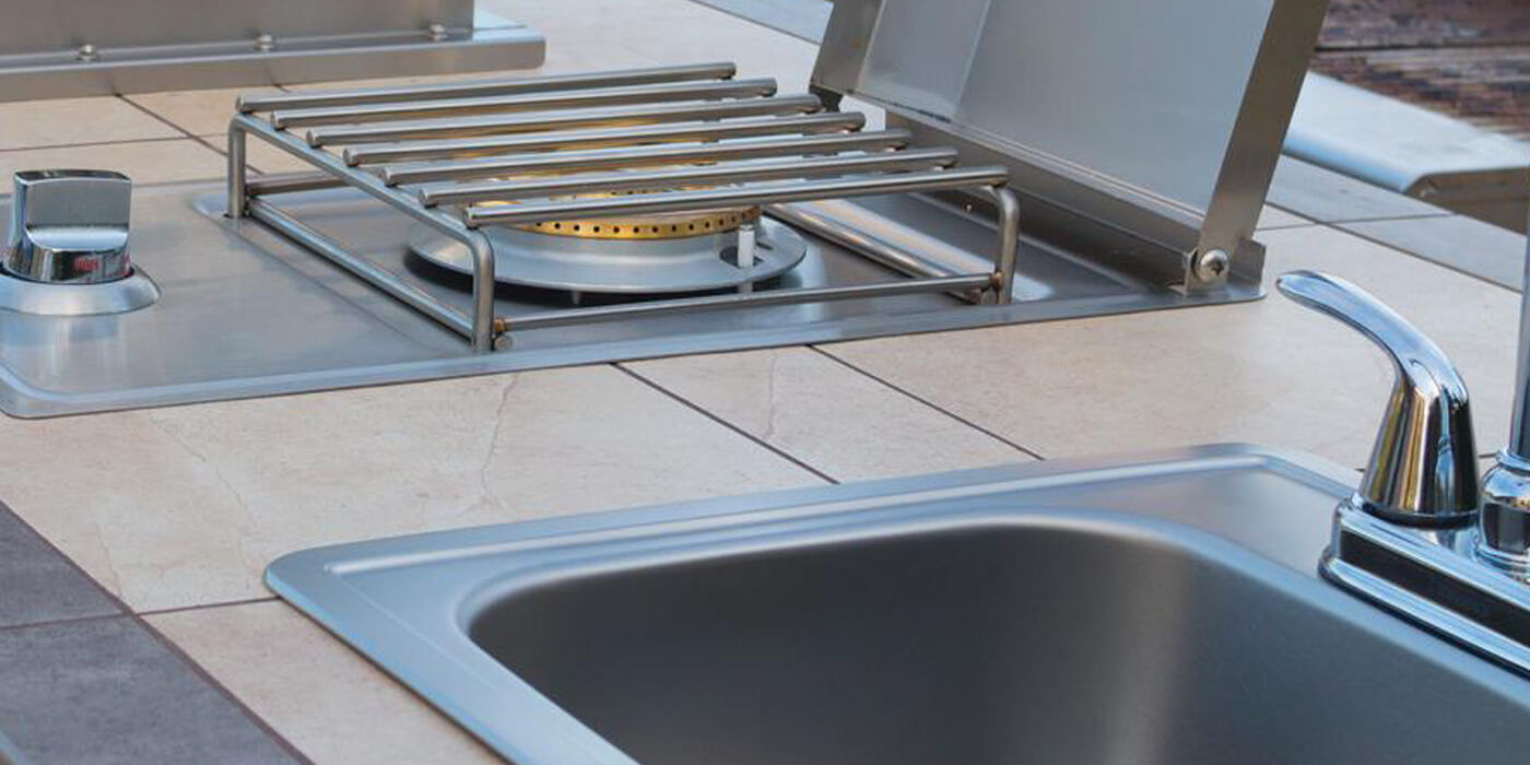 An outdoor kitchen with a side burner and sink 