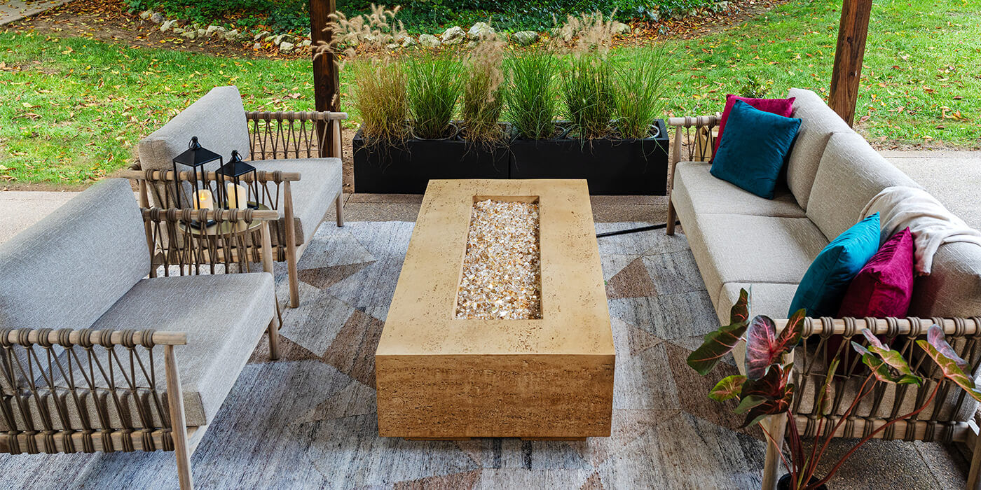 The FlameCraft Tuscan Gas Fire Pit installed on an outdoor deck with a patio furniture set from Three Birds Casual.