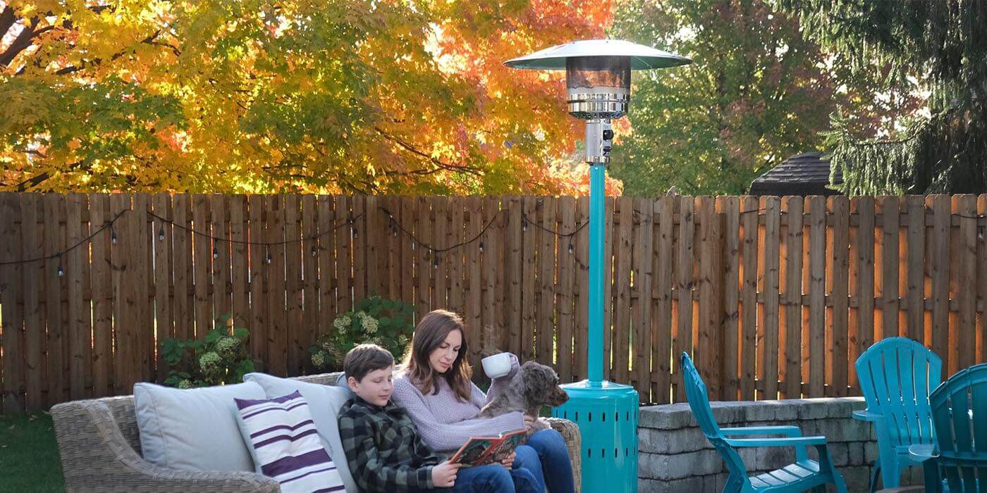 An aqua-colored freestanding propane patio heater installed in a residential backyard
