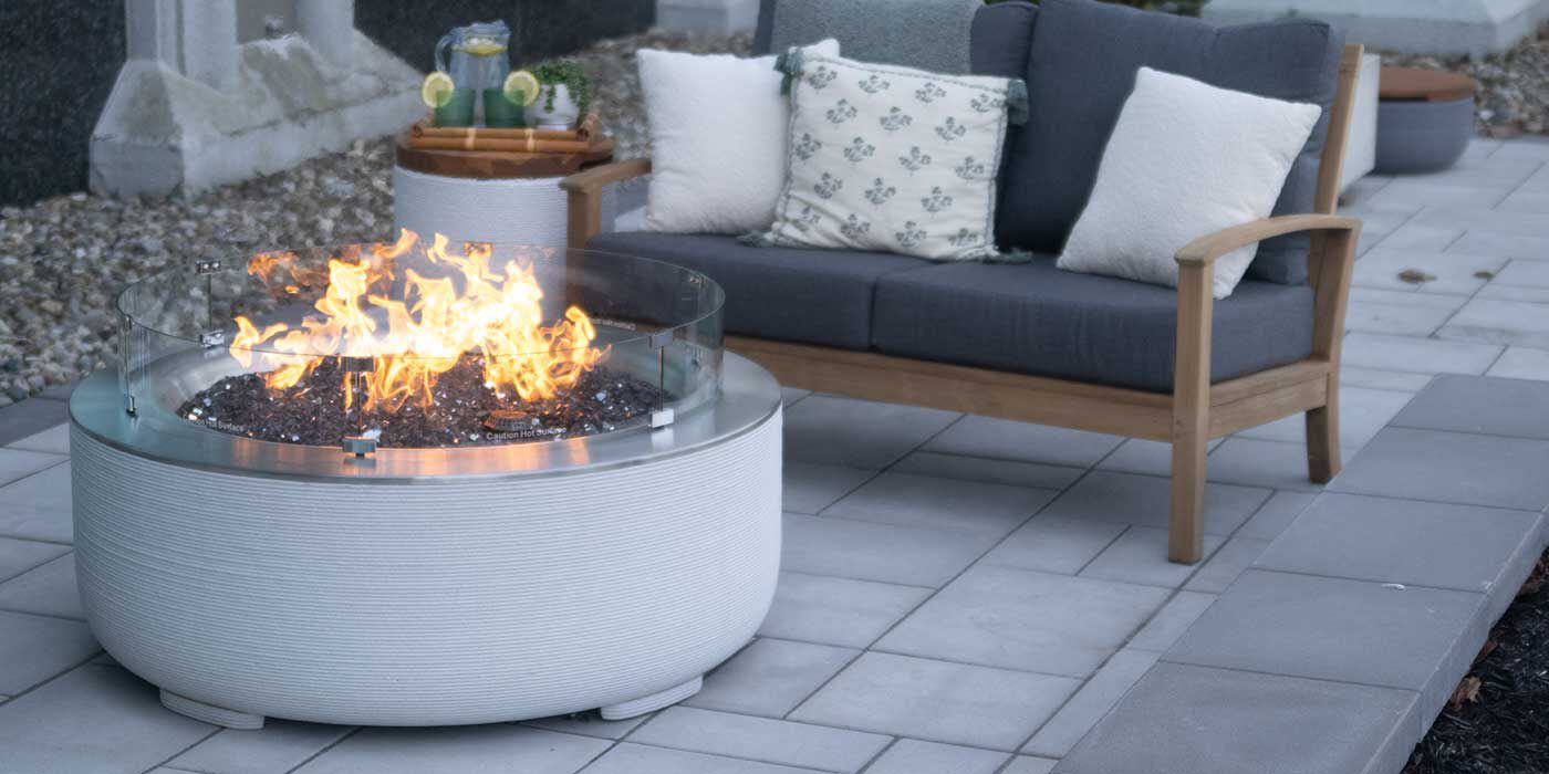 The ReForm Stack Gas Fire Pit by FlameCraft with a matching side table Propane tank enclosure and an outdoor sofa