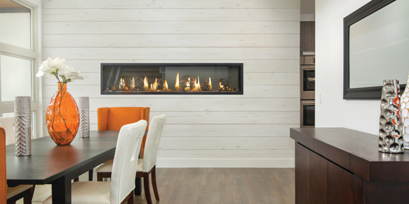 A linear gas fireplace installed on a shiplap covered wall in a dining room
