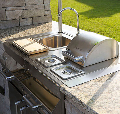 An outdoor kitchen with a stainless steel sink and faucet 