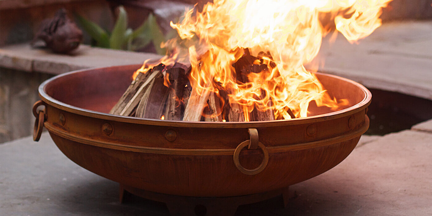 A large, decorative steel wood burning fire pit