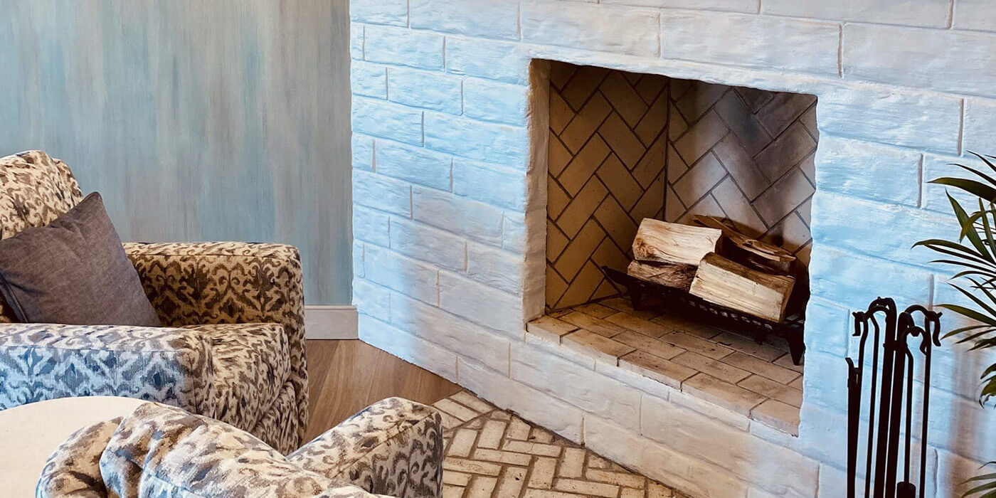 An unlit wood burning fireplace with a stack of seasoned firewood inside