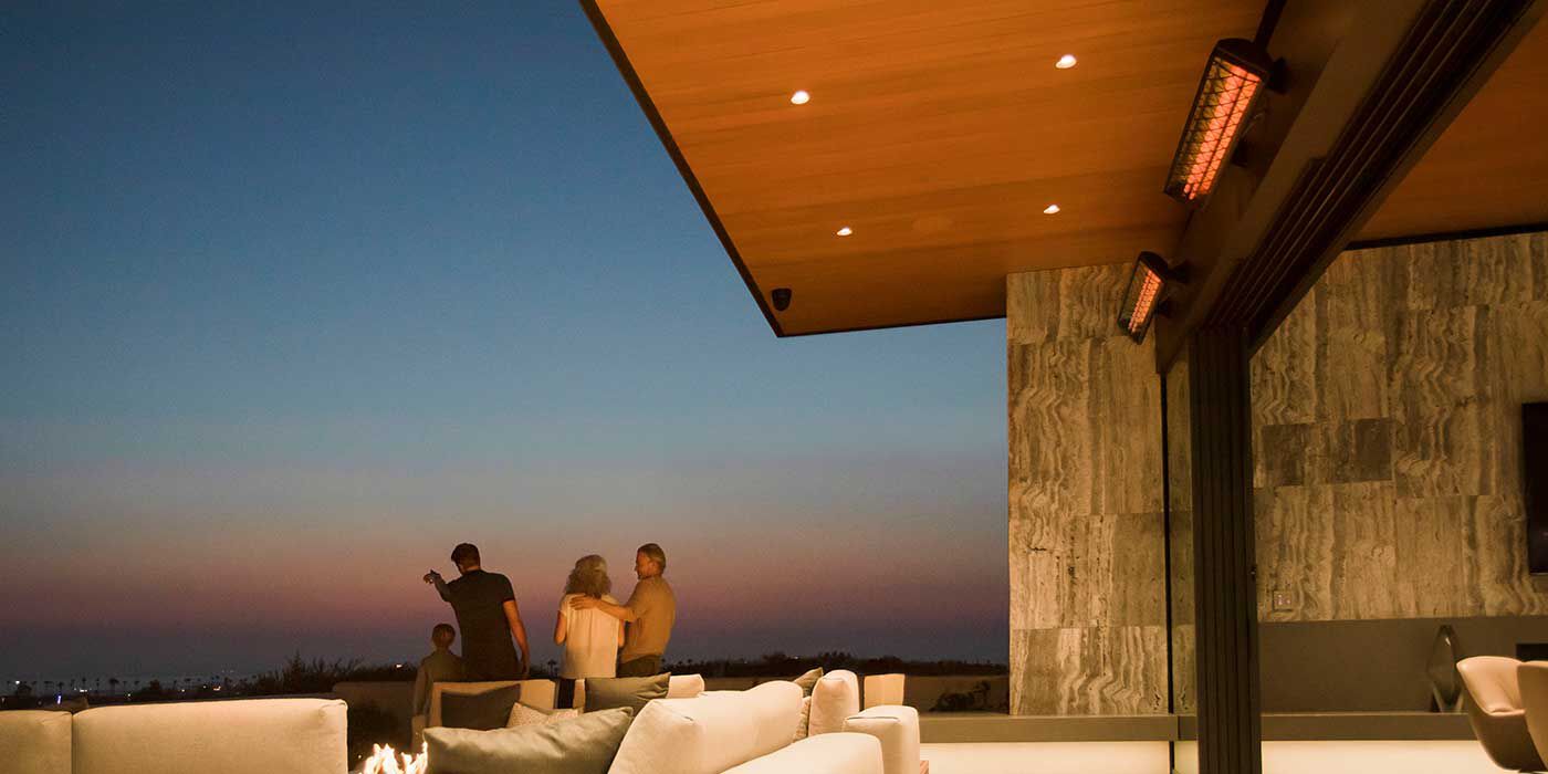 An outdoor lounge space at night with two Infratech patio heaters installed on the ceiling
