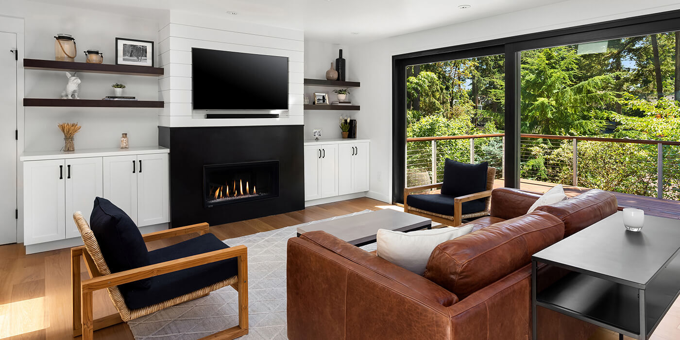 A transitional living room with a linear gas fireplace installed in a custom entertainment center, complete with floating shelves, cabinets, and a TV above the fireplace.
