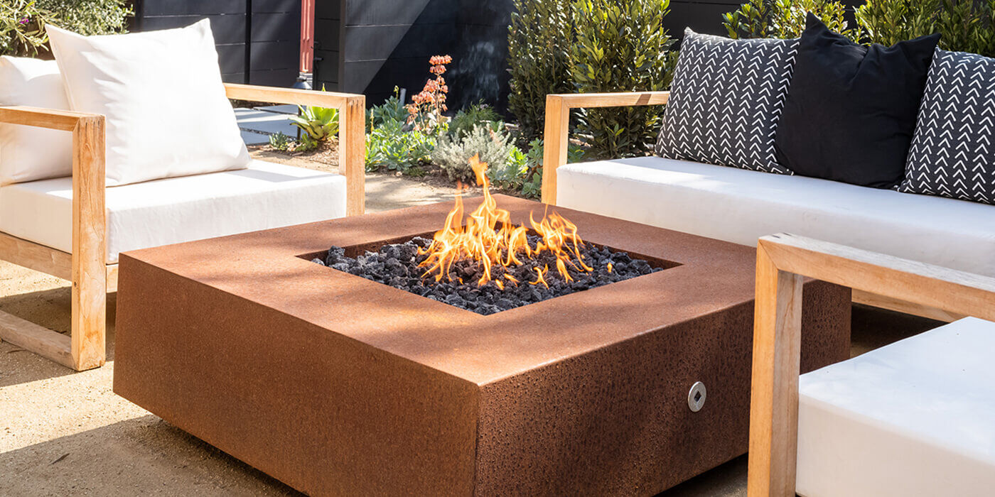A square Corten Steel gas fire pit from the brand The Outdoor Plus