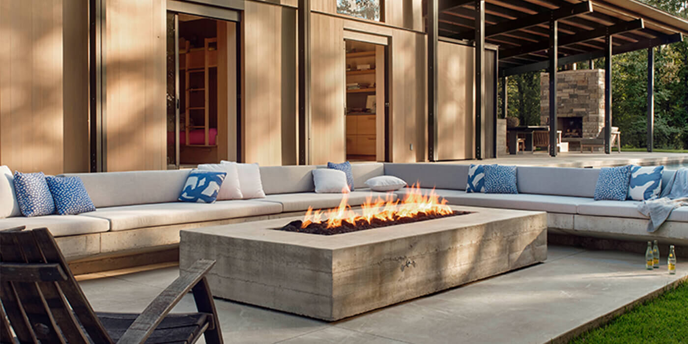 A clean, contemporary outdoor living space with a large, linear natural gas fire pit and a patio furniture set.