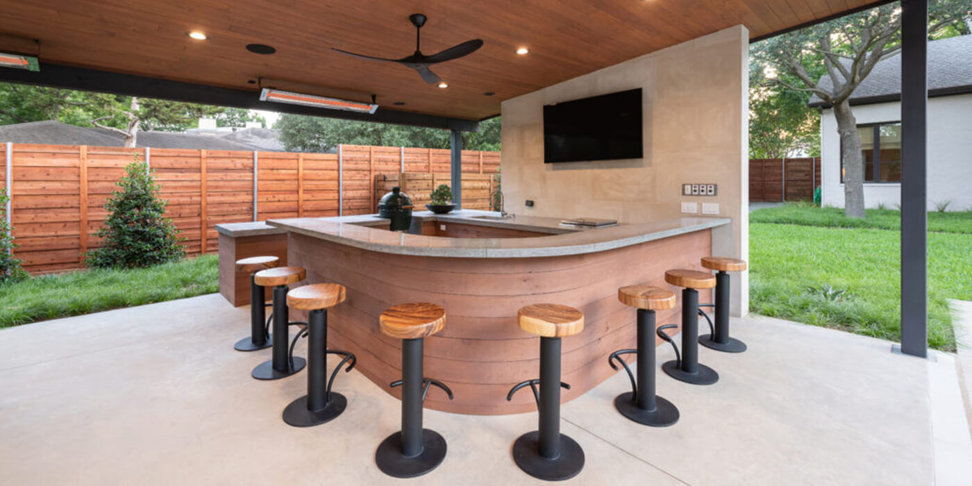An outdoor bar area with seating, a TV, and two mounted patio heaters