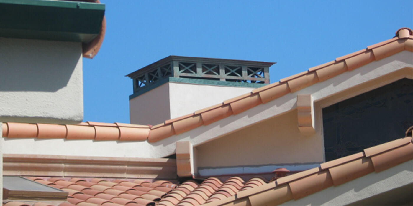 A large copper chimney shroud with a blue/green patina