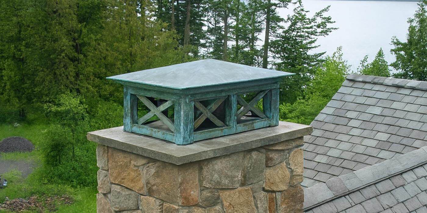 A copper chimney shroud with a blue/green patina 