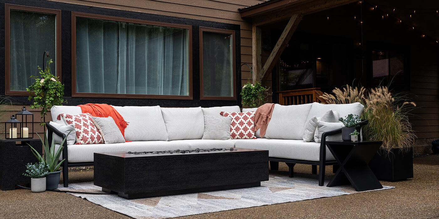 An outdoor patio with a large white sectional sofa and the black linear Zen Gas Fire Pit by FlameCraft