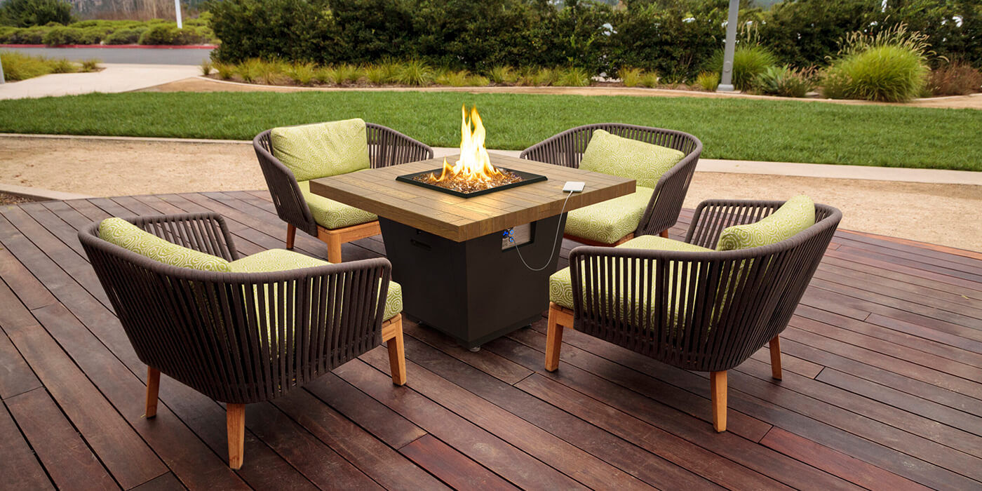 The Cosmo fire pit table from American Fyre Designs placed on an outdoor deck 