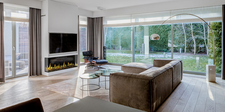 A large, modern home with a Modern Flames multi-sided electric fireplace installed under a flatscreen TV