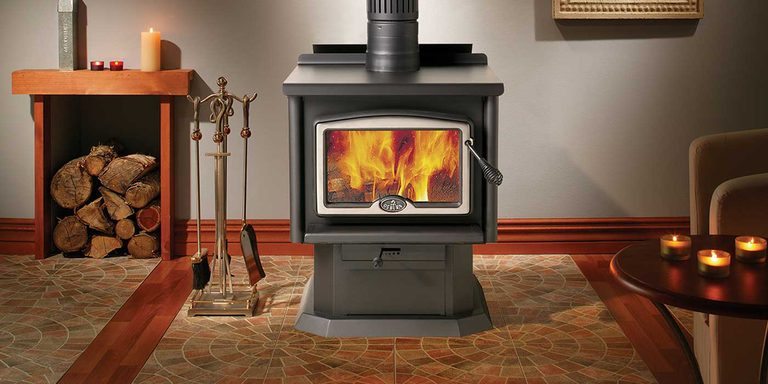A traditional living space with a large wood burning stove, fireplace tools, and a wood storage box